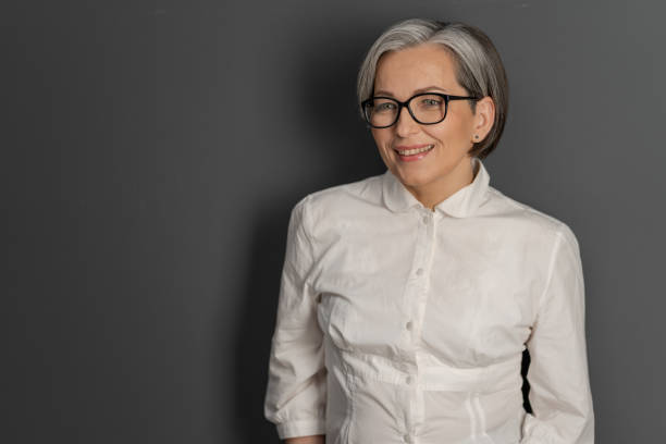 istock Intelligent middle aged woman with glasses smiling charmingly while looking at copy space on the left. Business concept. education or science concept 1238330913