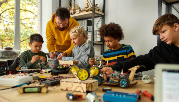 istock Focus on quality. Young technicians building a robot, working with a wiring kit together with a male teacher at a stem robotics class. Inventions and creativity for kids 1238338726