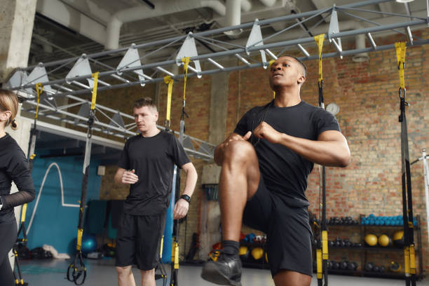 Two young adult men performing leg stretches in a modern gym, focused on their workout routine