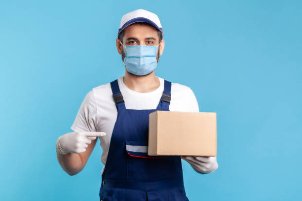 istock Cargo transportation, delivery service. Friendly worker in uniform pointing at cardboard box 1238384638