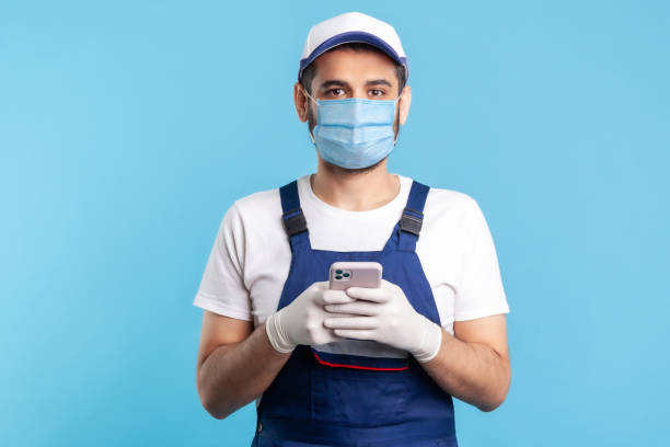 istock Handyman in overalls and gloves holding mobile phone, using cellphone messenger to accept online order 1238385086