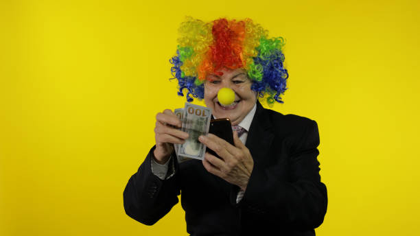 mulher de negócios palhaço freelancer recebe renda de dinheiro ao usar smartphone - clown circus telephone humor - fotografias e filmes do acervo