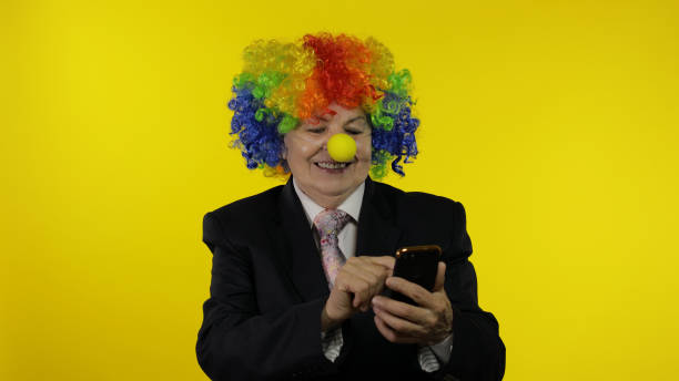 клоун бизнес-леди фрилансер с помощью приложения на смартфоне для онлайн удаленной работы - clown circus telephone humor стоковые фото и изображения