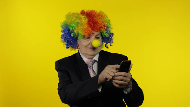 клоун бизнес-леди фрилансер с помощью приложения на смартфоне для онлайн у�даленной работы - clown circus telephone humor стоковые фото и изображения