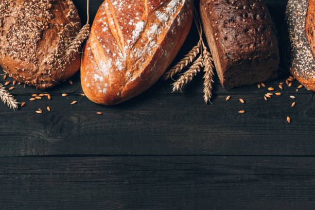 istock Bread border on wood background with copy space. Different types of bread arranged as frame with spikelets. Bakery, cooking and grocery store concept. 1238464359