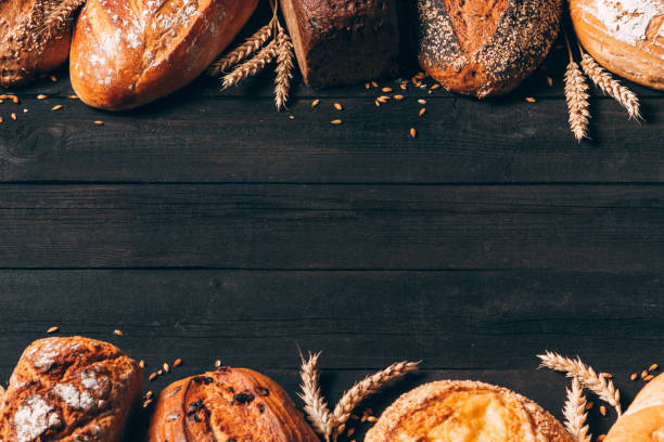 istock Bread border on wood background with copy space. Different types of bread arranged as frame with spikelets. Bakery, cooking and grocery store concept. 1238467955