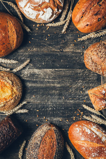 istock Bread border on wood background with copy space. Whole grain loaves with spikelets. Different types of bread arranged as frame. Bakery, cooking and grocery store concept. 1238469992