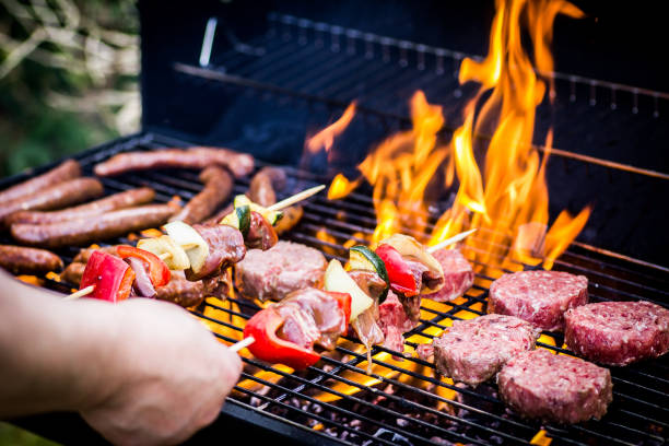 détail des hamburgers de boeuf et des saucisses cuisinant sur un barbecue - grillade photos et images de collection