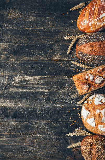 istock Bread border on wood background with copy space. Whole grain loaves with spikelets. Different types of bread. Bakery, cooking and grocery store concept. 1238485905