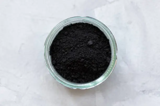 Photo of Black activated charcoal powder in a glass