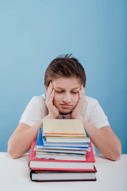 istock tired boy with books on the table, sitting at the table, 1238552949