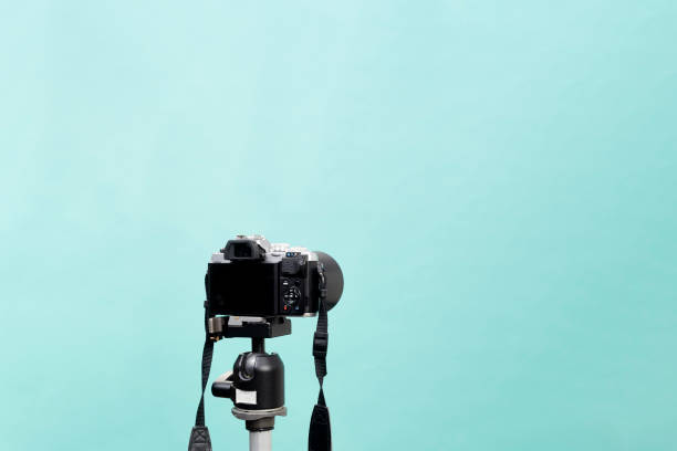parte de trás de uma câmera sem espelho em um tripé no estúdio fotográfico contra um cenário azul pastel - 16192 - fotografias e filmes do acervo