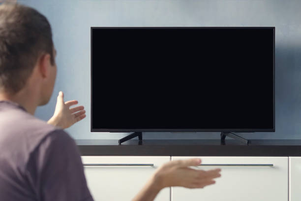 istock A young guy emotionally watching TV and waving his hands in discontent. Blank screen for design. Frustrated Man Sitting On Sofa In Front Of Television With No Signal. 1238587146