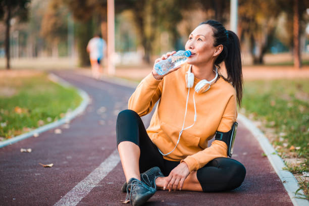 sportler sitzen und trinkwasser - exercising sensuality water bottle relaxation exercise stock-fotos und bilder