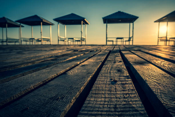 Empty summer cafe on the beach. No visitors due to pandemic and covid-19. Tables on a canopy, wooden flooring. Restaurant with sea view on the coastline. Closed borders, lack of tourists. Evening. Sunny. Georgia.