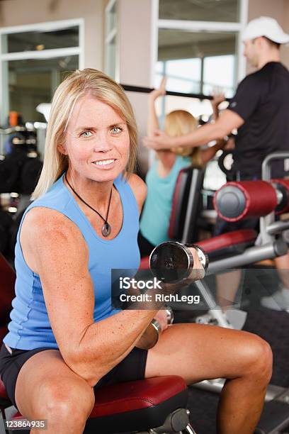 Mujer Levantamiento Pesas En El Gimnasio Foto de stock y más banco de imágenes de 40-49 años - 40-49 años, Actividades y técnicas de relajación, Adulto