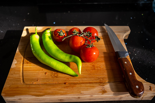 Top view of green peppers,tomatos and knife on wooden cutting board to prepare turkish eggplant kebab, patlican kebab with meatball