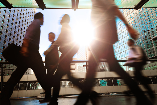 Blurred silhouettes of businesspeople walking in Hong Kong’s Central District elevated walkway