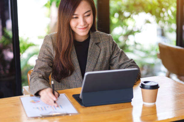 istock a beautiful asian businesswoman working and using digital tablet as a computer pc with financial document on the table 1238901695
