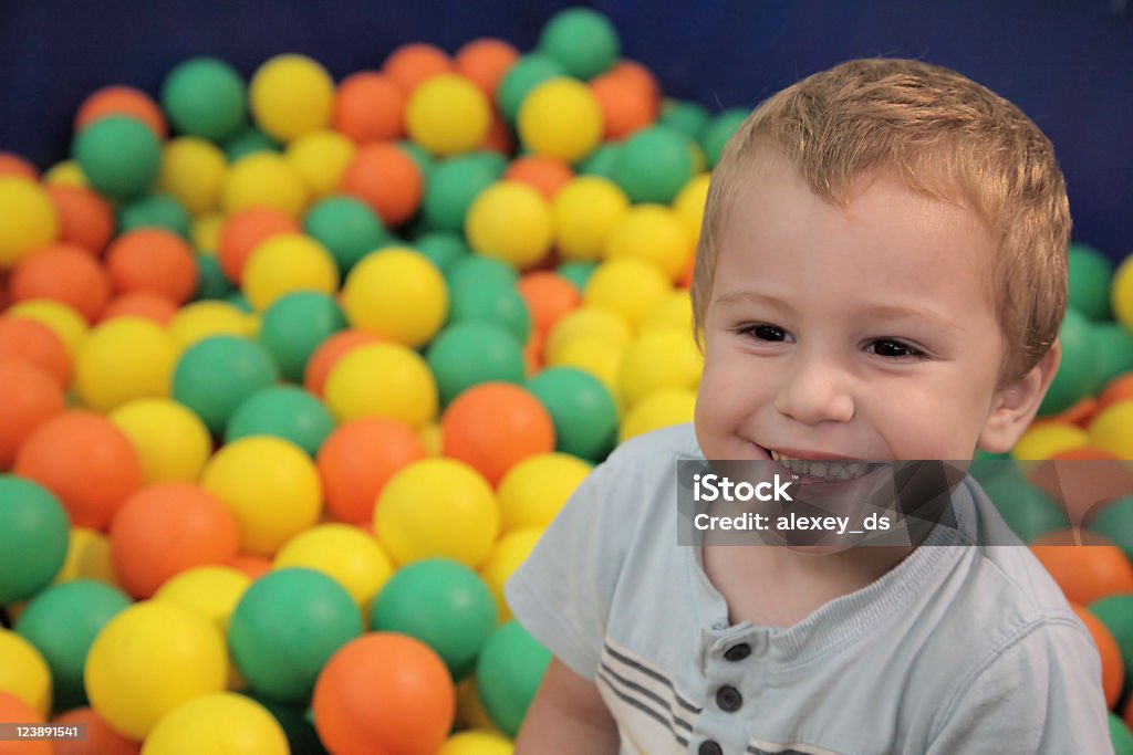 Bambino felice in sfere multicolore - Foto stock royalty-free di Adulto