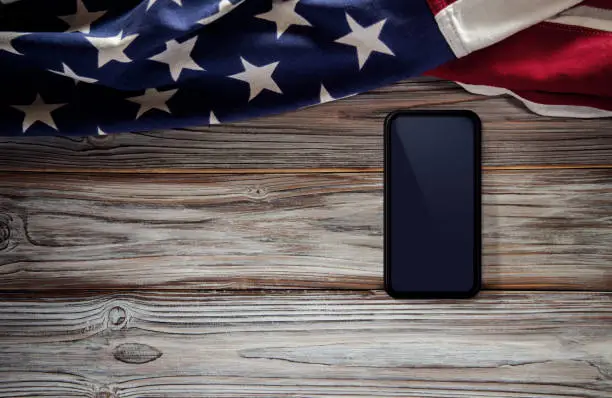 4th of July or Memorial Day of United States Concept. Blank Mobile Screen for Mockup. USA Flag Lying on Wooden Background. American Symbolic. Top View