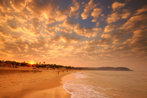 Stock photo showing sandy beach along water's edge with island on horizon, Palolem Beach, Goa, India.