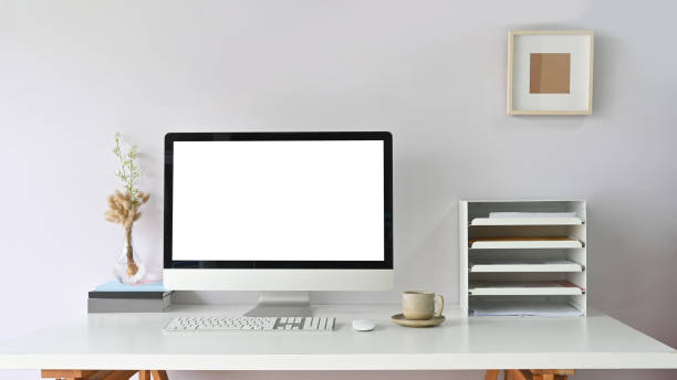 istock Workspace Computer monitor with white blank screen putting on working desk and surrounded by bookshelf, mouse, keyboard, coffee cup. 1238977883
