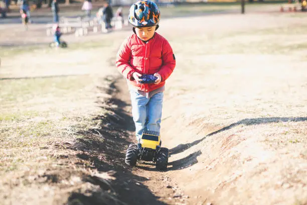 Photo of Boy playing a radio‐controlled model car in the park