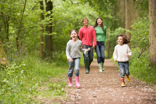 Family walking on woodland path smiling