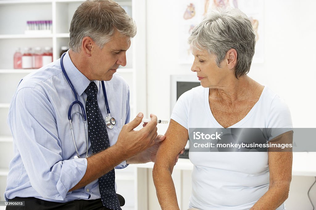 Lekarz z kobieta pacjenta, dając jej zastrzyku - Zbiór zdjęć royalty-free (50-59 lat)