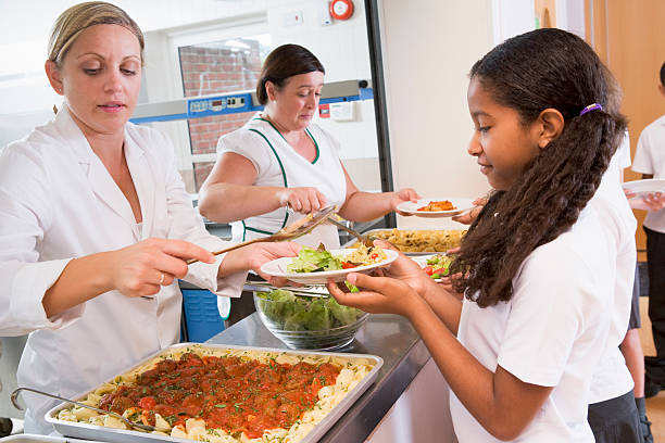 Schoolgirl holding plate of lunch in school cafeteria Schoolgirl holding plate being served food in school cafeteria cafeteria worker photos stock pictures, royalty-free photos & images