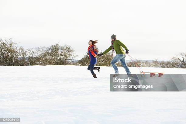 Teenage Couple Pulling Sledge Across Snowy Field Stock Photo - Download Image Now - 20-29 Years, Adult, Affectionate