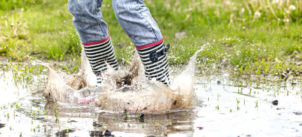 istock A child in rubber boots jumps in a puddle. 1239060907