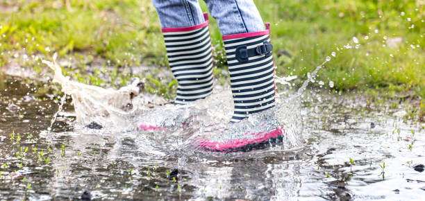 istock A child in rubber boots jumps in a puddle. 1239060908