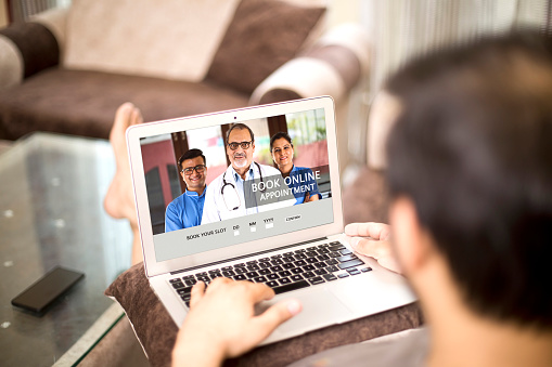 Booking online appointment with doctors using laptop at home