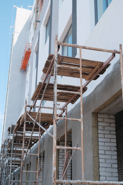 istock Empty scaffolding near the building with spread out work items - ropes, buckets, uniforms and a ladder 1239080347
