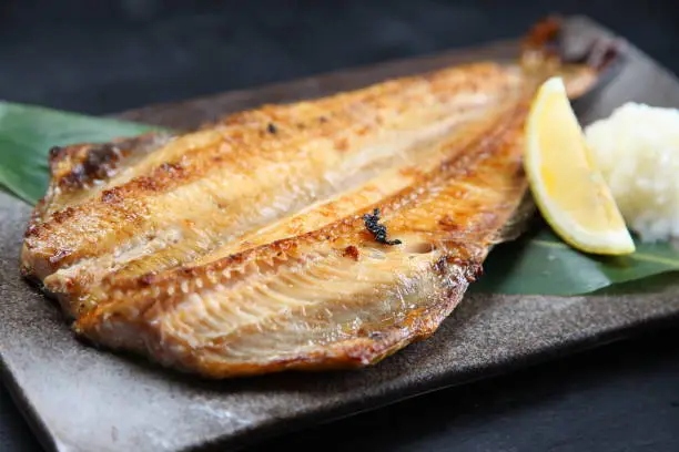 roasted atka mackerel with lemon on dark background