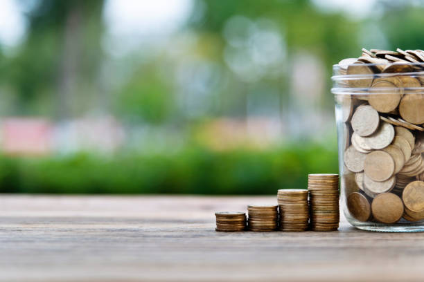 Coin stairs and jar on wooden table