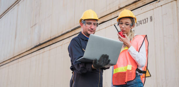 istock Two foreman man & woman worker working checking at Container cargo harbor holding laptop computer and using walkie-talkie to loading containers. Dock male and female staff business Logistics import export shipping concept. 1239162018