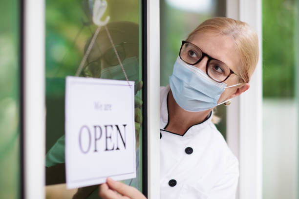 Cafe opening after lockdown. Open door sign. Cafe opening after lockdown. Open sign on front door of restaurant or grocery store. Waiter in apron greeting customer. Welcome message on bakery entrance. Back to work after quarantine. lockdown business stock pictures, royalty-free photos & images