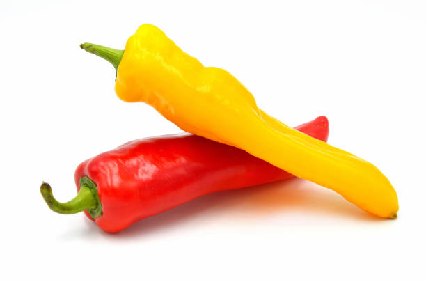 close up red and yellow pointed paprika on white background
