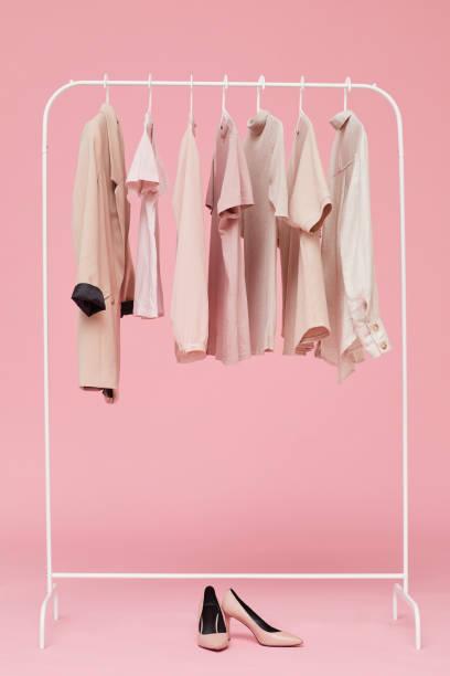 Sets of clothes on a hanger Image of sets of clothes hanging on hanger with shoes on the floor isolated on pink background coathanger stock pictures, royalty-free photos & images