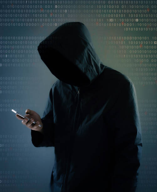 istock Internet crime concept,Hooded hacker using smartphone in dark room 1239189244
