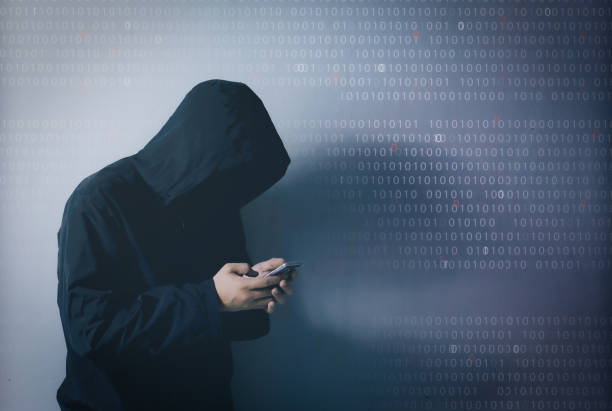 istock Internet crime concept,Hooded hacker using smartphone in dark room 1239189797