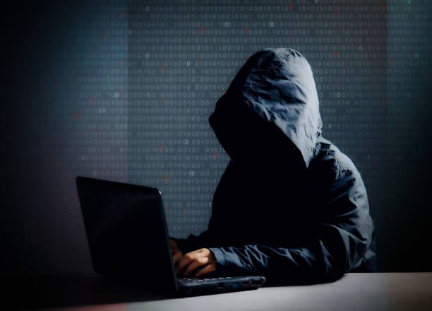 istock Internet crime concept,Hooded hacker using laptop in dark room 1239190885