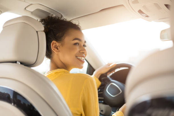 明るい黒人女性が自動車に座って車を運転, バックビュー - car african descent shopping car dealership ストックフォトと画像