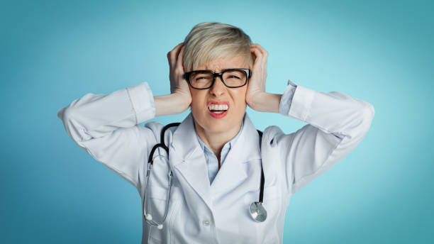 istock Headache from problems in medicine. Upset doctor holds her head with hands and closes eyes 1239233901