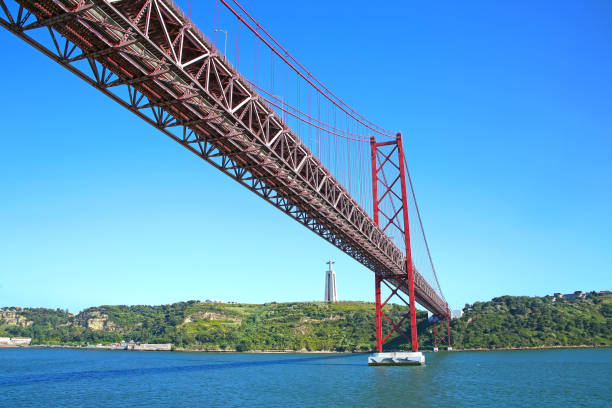 25 de abril hängebrücke verbindet die stadt lissabon, die gemeinde almada & die christusstatue im hintergrund, die hoch über den südlichen ufern der tejo-mündung, lissabon, portugal steht. - suspension railway stock-fotos und bilder