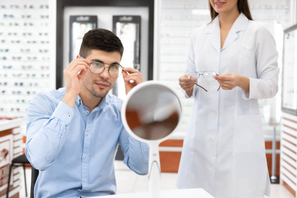 istock Specialist helping young guy to choose glasses 1239246827