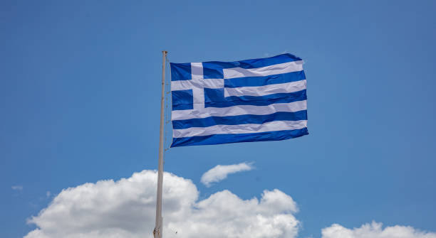 istock Greek flag waving against blue sky background 1239261613